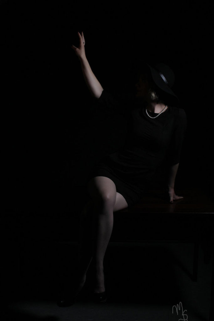 Imagen oscura de una mujer sentada, con las piernas cruzadas.